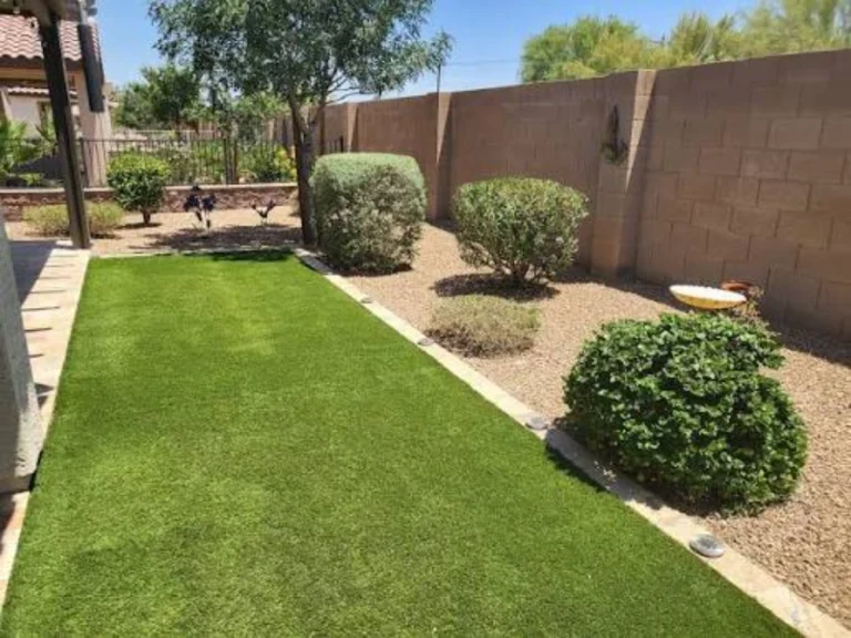 Backyard with artificial turf strip, gravel beds and low-water shrubs against a block wall