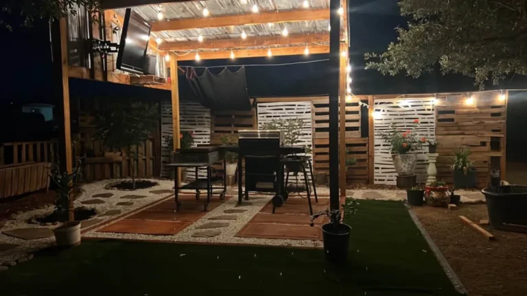 Backyard pergola with string lights, pavers, white gravel and artificial turf at night